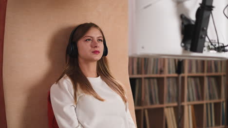 woman with headphones watches video in library. young lady student learns material with digital technology in university. visual information study