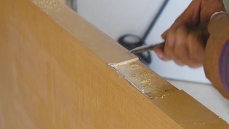 a male construction worker manually chipping away at a door so door hinges fit securely