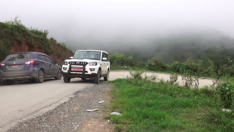 kathmandu, nepal - september 27, 2019: traffic and vehicles on a dangerous, muddy mountain road in the foothills of kathmandu, nepal on september 27, 2019.