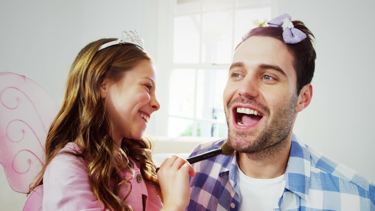 Girl dressed up in a fairy costume applying make-up on fathers face