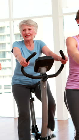 grupo de mujeres sonrientes haciendo una clase de spinning