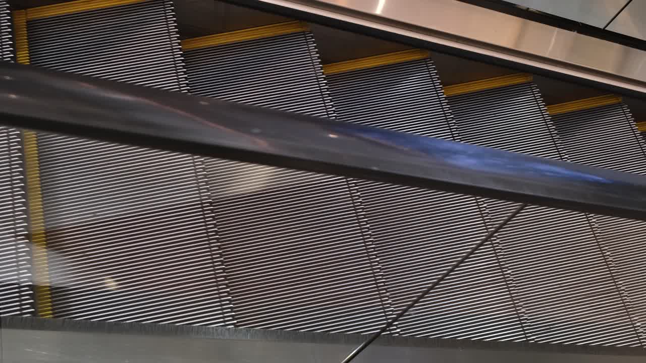 An empty escalator moving downwards inside a commercial centre in a business area in Southeast Asia
