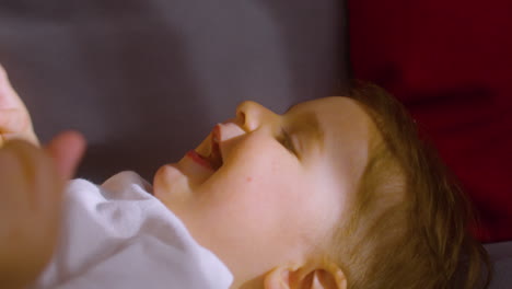 vista de cerca de un bebé sonriente acostado en el sofá en casa mientras su madre le hace cosquillas y juega con él 2