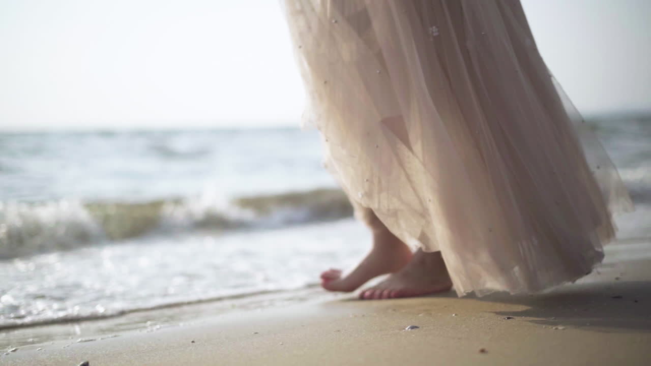 Slow motion.Women walking barefoot by the beach while the sun sets.Waves at sunset.