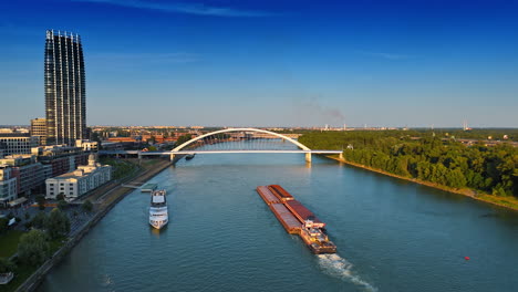 barge pushing the loads by the danube towards the appolo bridge. riverboat travel along the shore. aerial view. bratislava, slovakia