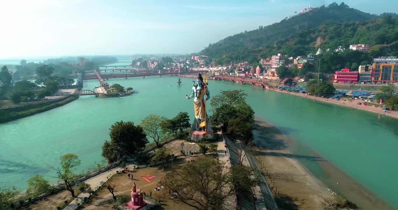Hermosa toma lateral frontal de una gran estatua del dios hindú Shiva observando los sagrados Ghats del Ganges de la ciudad santa de Haridwar, Uttarakhand, India