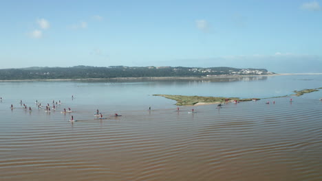 peaceful ocean with people in stand up paddle boarding wearing santa claus costume at obidos lagoon, portugal