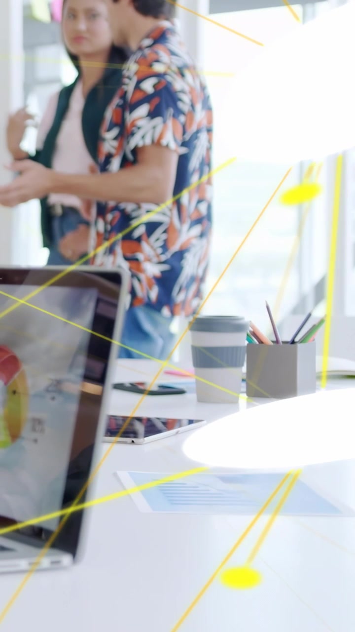 Vertikal video: Mand går hen til kvinde, der viser diagram på kontor, mens gule linjer fejer hen over skrivebord