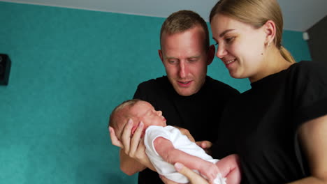 caucasian parent take care of their newborn child. woman is waving a kid and man tries to wake him up. low angle view.