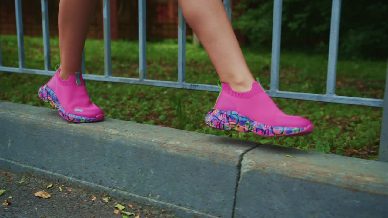 A Vibrant Display of Footwear: A Close-Up View of Stylish Pink Shoes Amidst Urban Surroundings, Showcasing Comfort and Trendy Design on the Edge of a Sidewalk