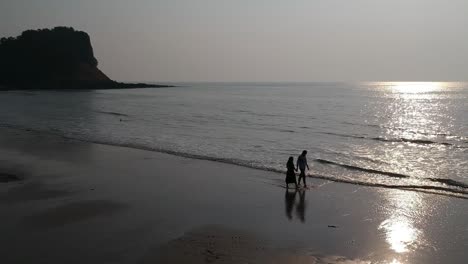 couple walking at beach - aerial drone video