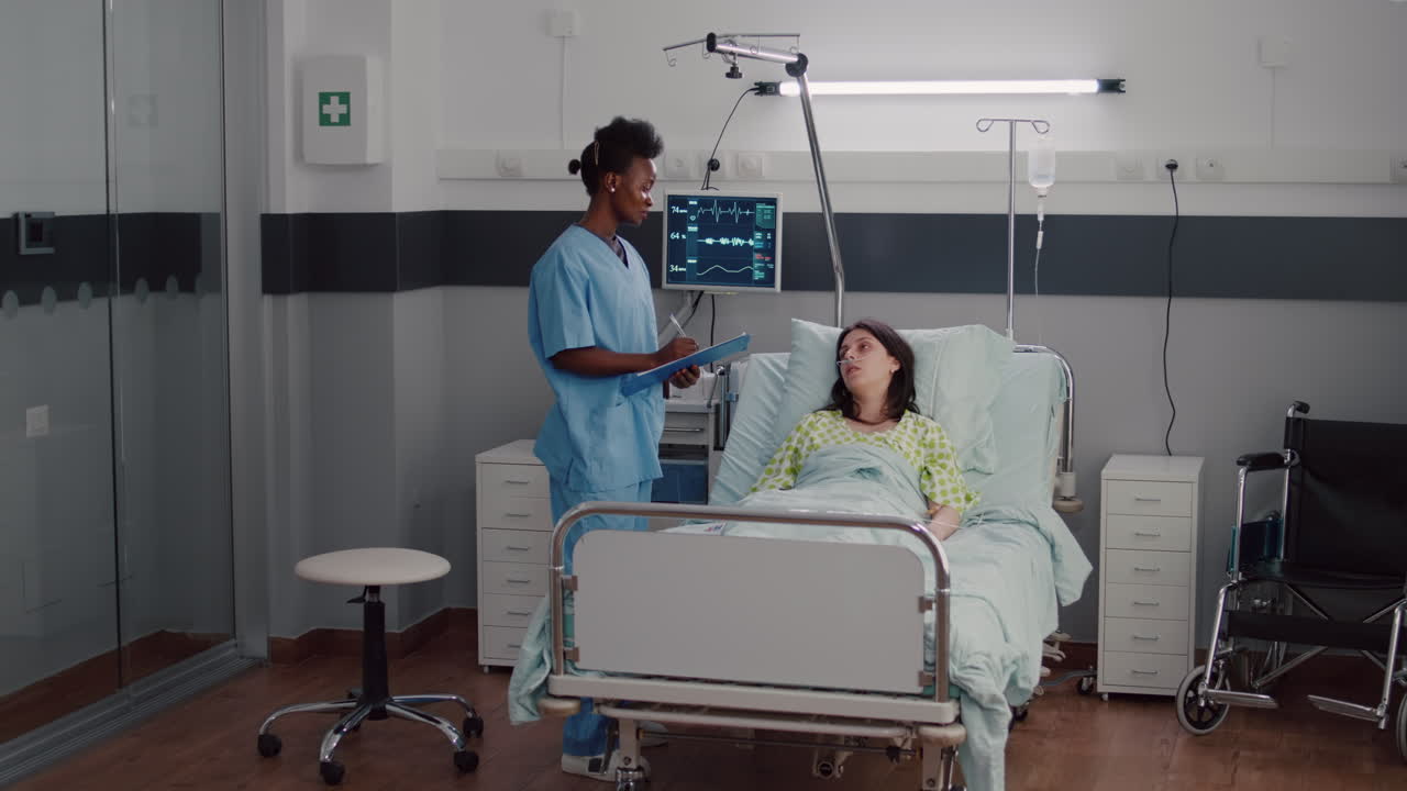 primer plano de la enfermera afroamericana que vigila a una mujer enferma mientras descansa en la cama