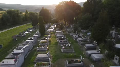 Low-flyover-above-large-gravestones-in-cemetery-near-Varbo,-Hungary,-sunset