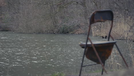 soft focus on a worn and rusty chair at a forest waterfront, static