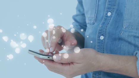 animation of multiple white spots over midsection of man using smartphone on blue background