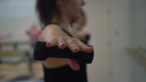 a close up of a lady hands in a gym excercising of her hands with small dumbbless in a gym