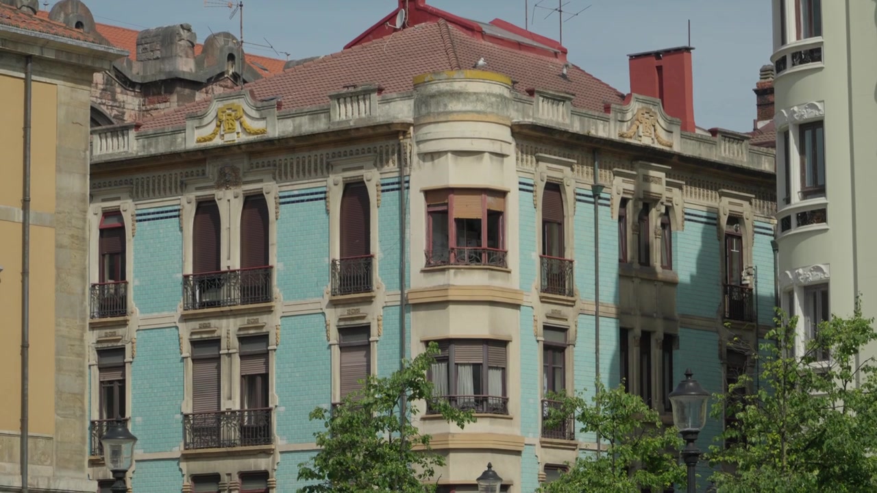 Inquadratura media di un bellissimo edificio storico tradizionale con una facciata in piastrelle azzurro chiaro, finestre ornate e balconi in Plaza del Parchis a Gijon, Asturie, Spagna