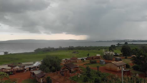 aerial over african village with a big tropical storm over lake victoria