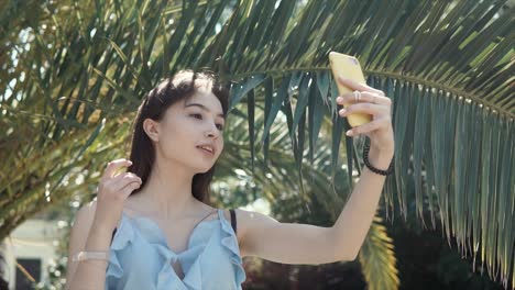 young woman taking a selfie under palm trees