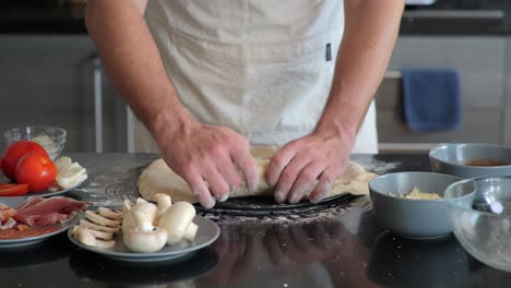 a pizza chef stretches pizza dough over a pizza pan