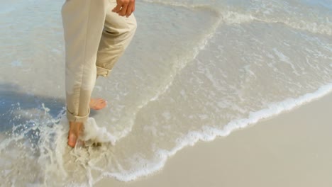 low section of active senior african american woman walking on beach in the sunshine 4k