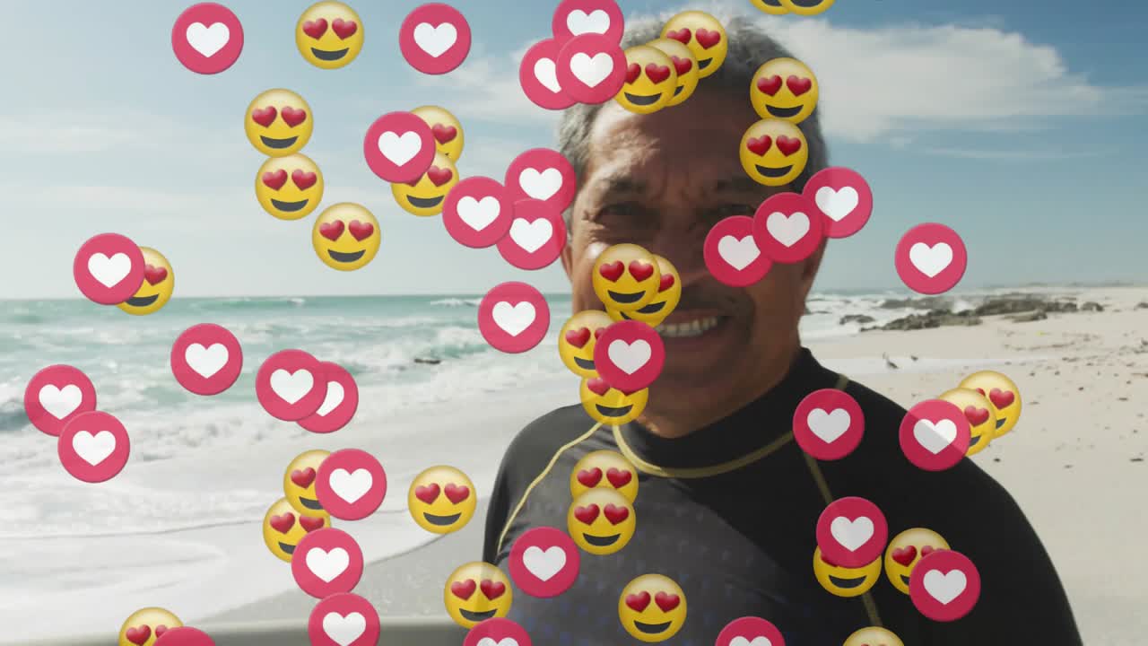 Surfista mayor de pie en la playa, iniciando íconos de redes sociales a la deriva que muestran amor arremolinándose alrededor de la tabla