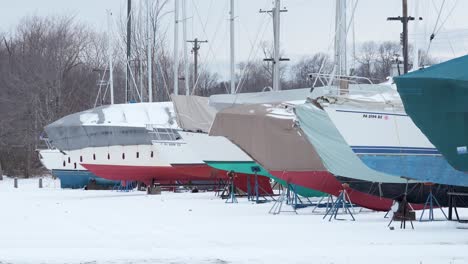 wide shot of boats on shore covered up for the winter