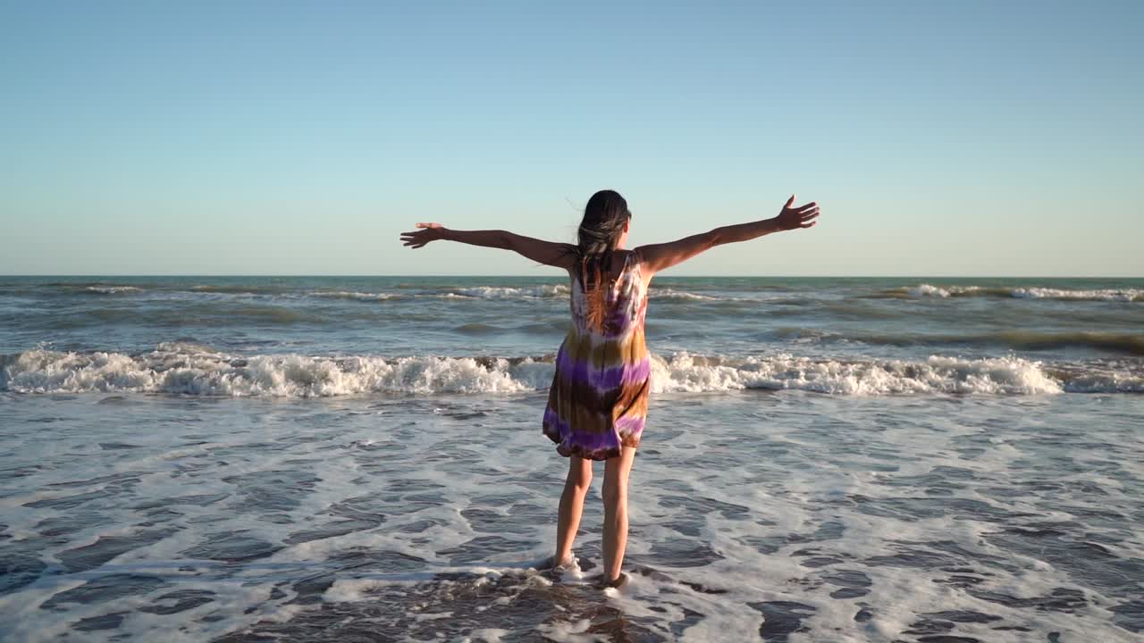 View Behind Happy Lady Standing With Open Arms At The Beach, Expressing Freedom And Blissfulness. wide, slow motion