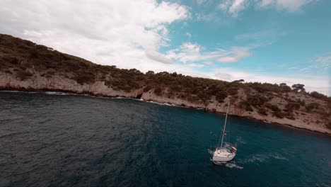 fpv aerial of an amazing sailboat motoring his way out of the bay in europe