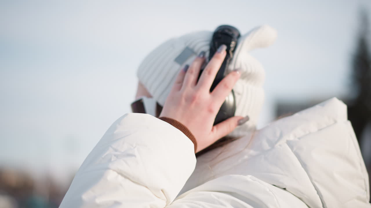 Side view of creative wearing headphones and futuristic goggles while swaying arms gracefully on snowy urban plaza, conveying free spirited joy and stylish winter outfit, rhythmic movement