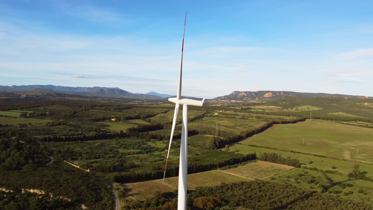 Paesaggio rurale con parco eolico e enormi turbine alte con pale rotanti in una giornata ventosa