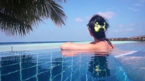 Girl-looking-at-the-ocean-while-sitting-by-the-pool