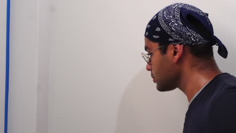hombre pintando la pared de la habitación con pincel y pintura de color blanco - de cerca