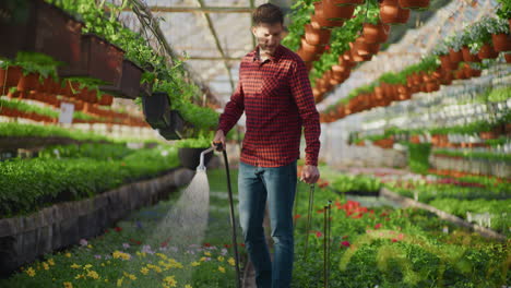 gardener watering flowers in large greenhouse