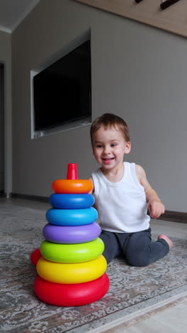 energetic caucasian toddler building a pyramid sitting on the floor. cute baby boy playing at home with toys. vertical video.