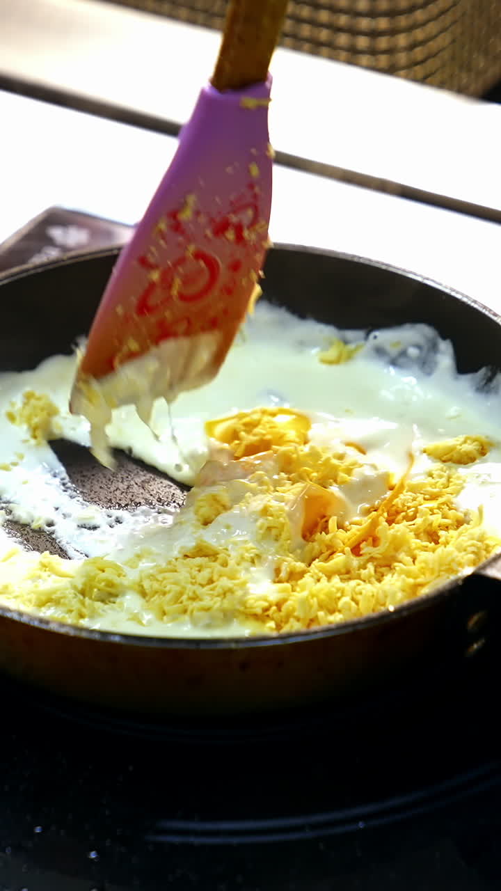 Cooking food in a frying pan. Chef is frying tasty dish in white sauce and mixing it with a scapula. Cooking delicious meal in a restaurant. Vertical video