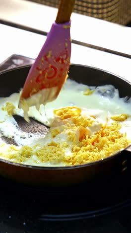 cooking food in a frying pan. chef is frying tasty dish in white sauce and mixing it with a scapula. cooking delicious meal in a restaurant. vertical video