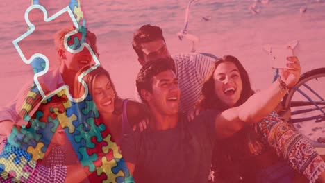 Animation-of-colourful-puzzle-pieces-ribbon-over-happy-friends-taking-selfies-at-summer-beach-party