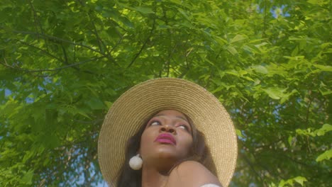 Mujer-Negra-Mirando-Alrededor-Ajustando-El-Cabello-Sonriendo-En-Un-Picnic-En-El-Parque-De-Inclinación-De-ángulo-Bajo