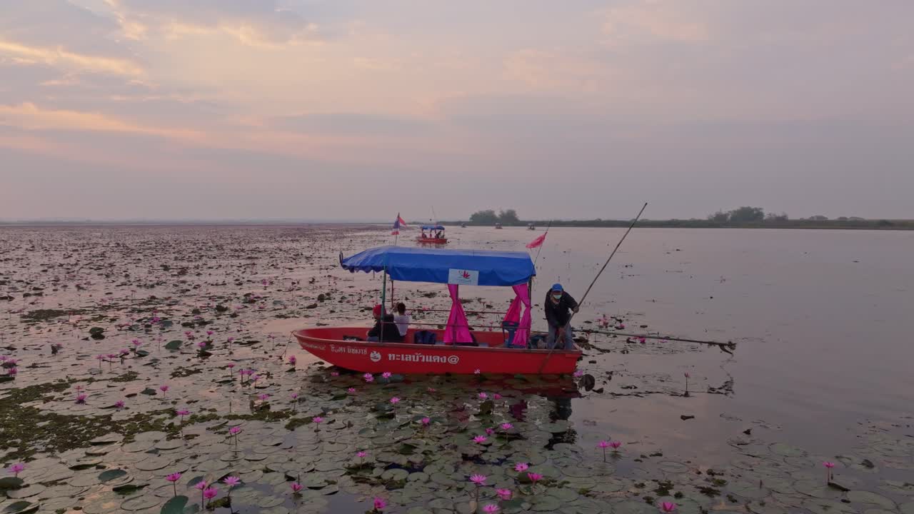Båter i soloppgang glir over rolige farvann i Udon Thani, Thailand