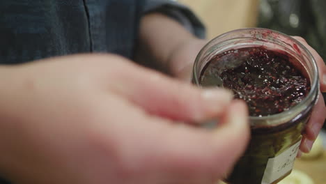 scooping jam out of a jar with a spoon