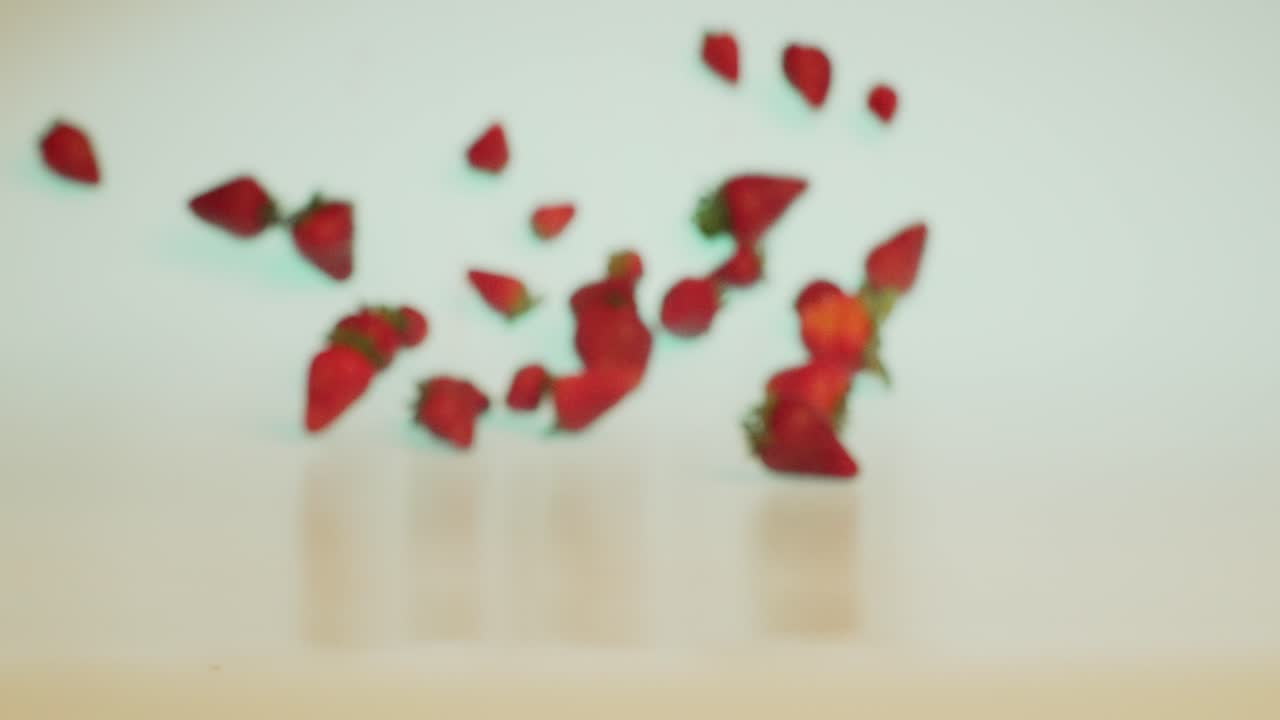 Organic health food, fresh and ripe strawberries falling and rolling forward in slow motion, creative concept shot