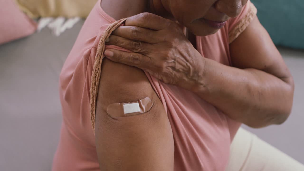 primer plano de una mujer mayor afroamericana que muestra la curita en su hombro