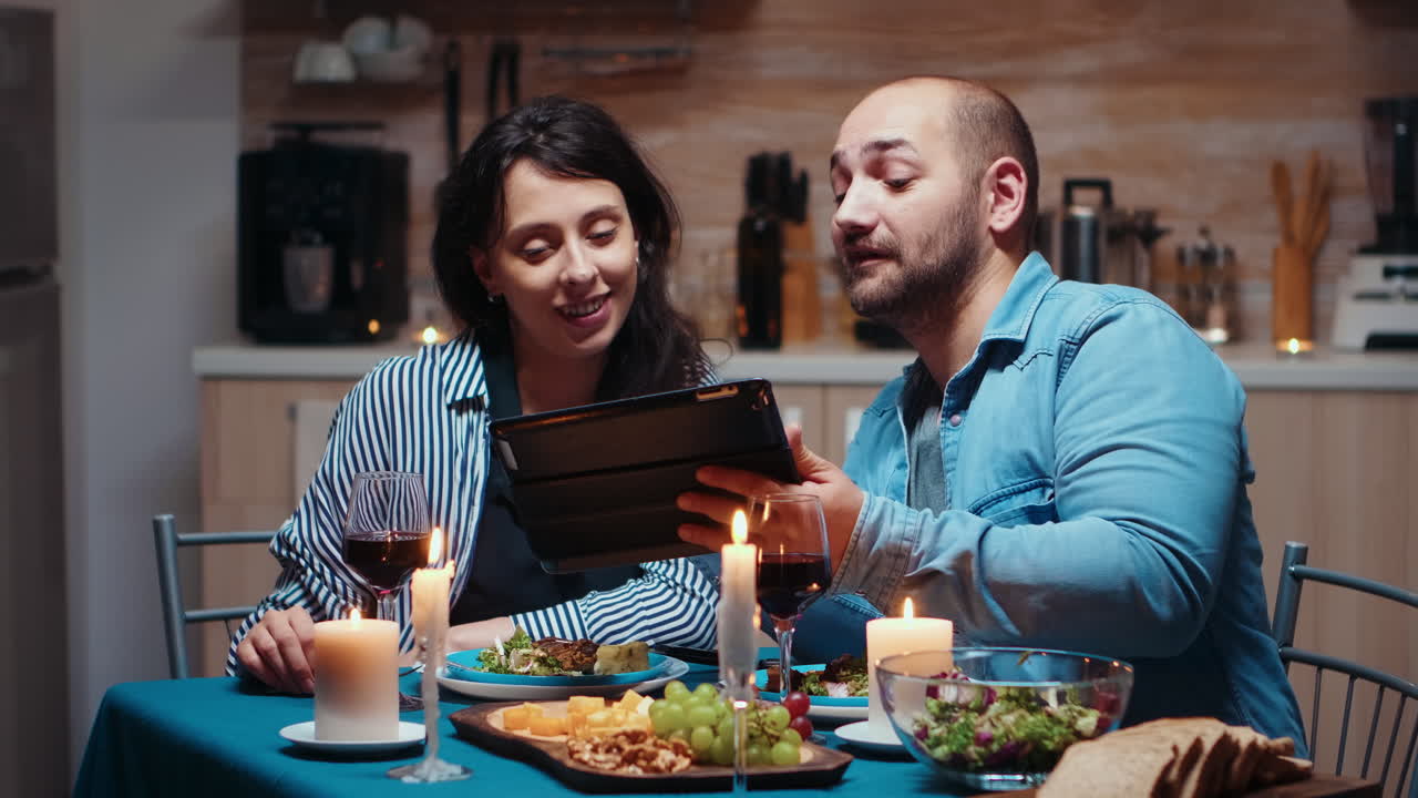marido usando la tableta durante la comida festiva