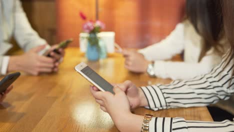 manos femeninas usando iphones y escribiendo en un acogedor café