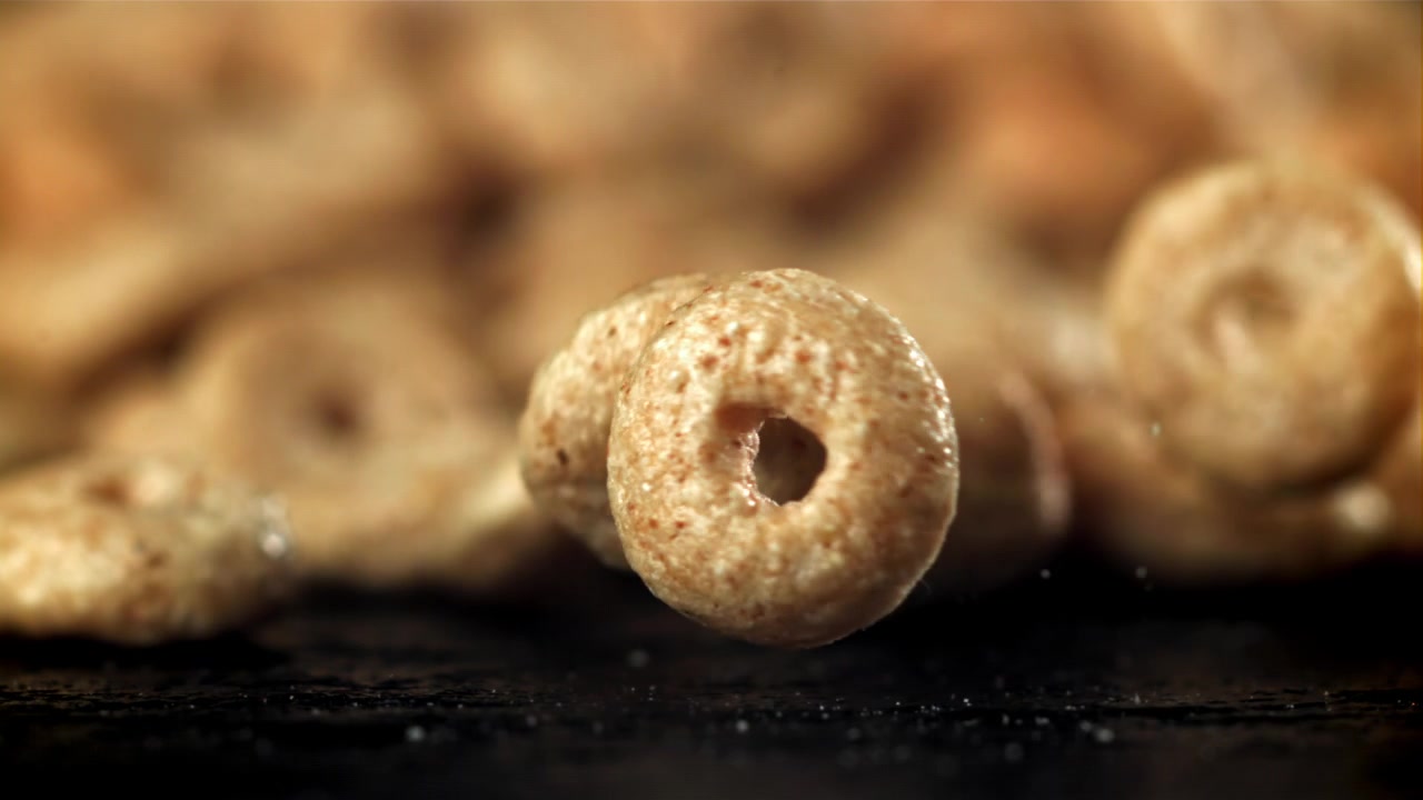 Anelli di cereali dorati che cadono in super rallentatore