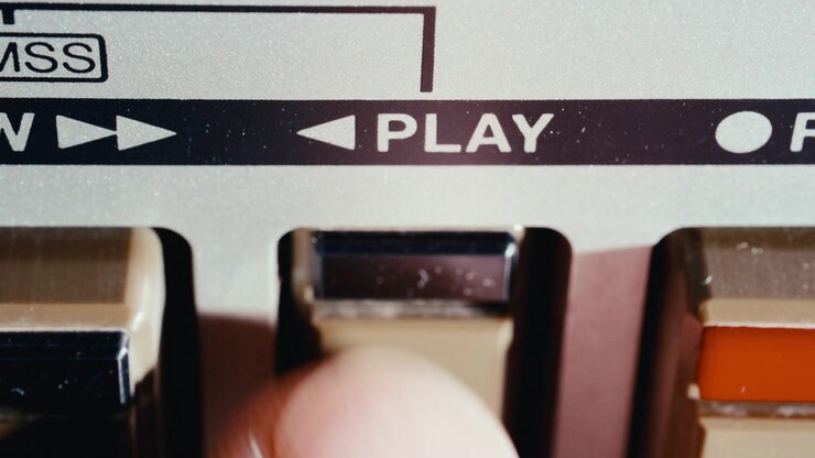 Dito che preme il tasto play su un registratore a cassette audio retrò