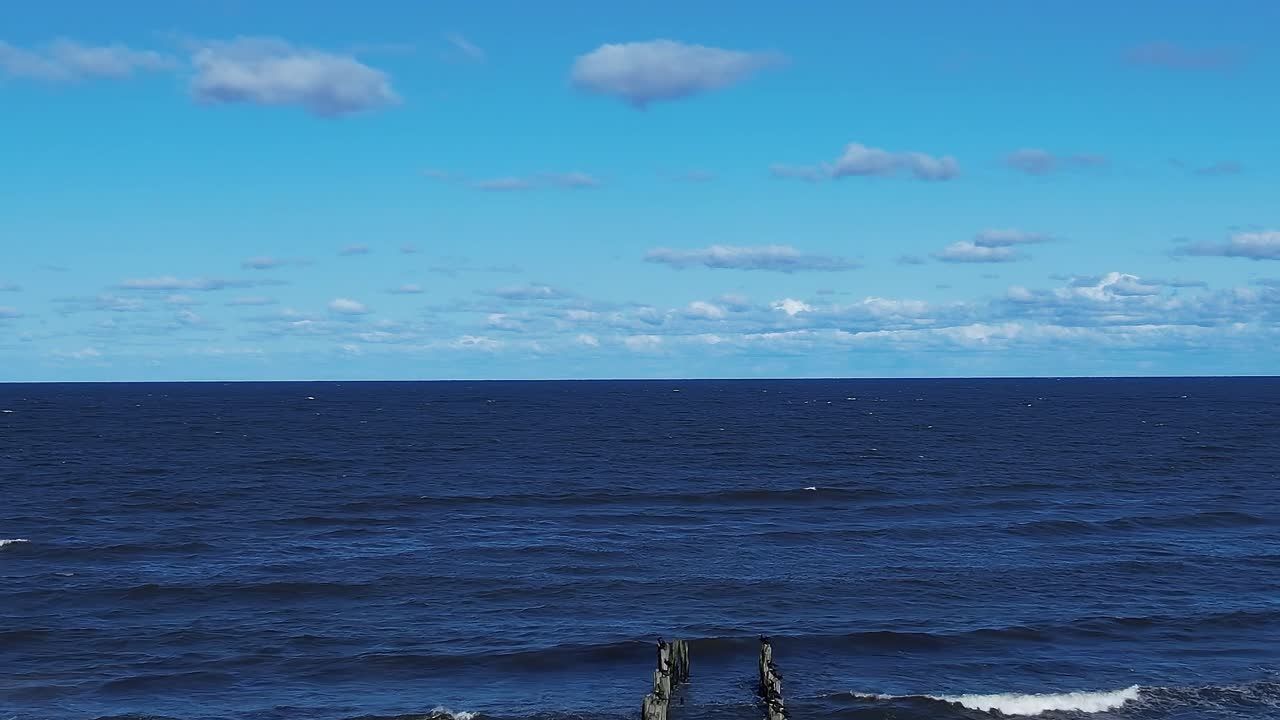 Bølger ruller blidt i Østersøen under en klar blå himmel