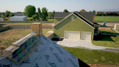 a drone shot back away passing a newly framed house with shingles ready to be placed on top