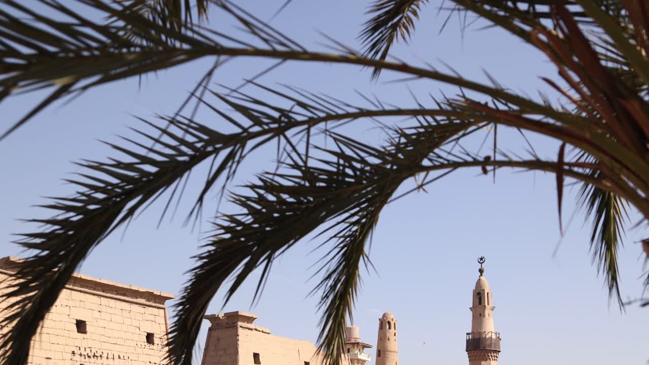 panorámica de las ruinas del antiguo templo de luxor con una mezquita y un minarete con palmera